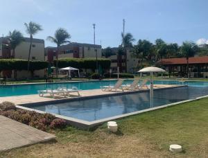 a swimming pool with lounge chairs and an umbrella at Apartamento térreo no Morro Branco Marina II in Beberibe