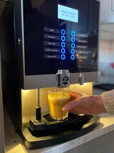 a person is making a cup of coffee in a espresso machine at Stationshuset bed and breakfast i Ed in Ed