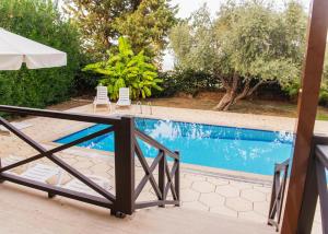 a swimming pool with two chairs and a umbrella at Villa Cyprium in Kyrenia