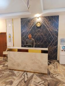 a man standing at a reception desk in a room at Ambassador Suites in Dargai