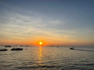 a sunset over the ocean with boats in the water at Authentic Joe homestay in Siem Reap