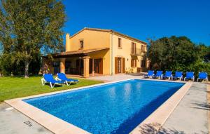 a swimming pool with blue chairs and a house at Can Bernat in Cala Mendia