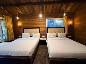 two beds in a room with wooden walls and windows at Royal cottage by royale palace in Mount Ābu