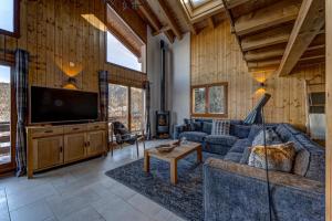 a living room with a couch and a tv at Chalet Renard Roux in La Tzoumaz