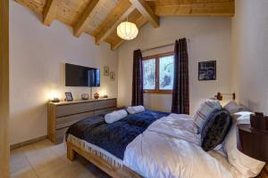 a bedroom with a large bed and a television at Chalet Renard Roux in La Tzoumaz