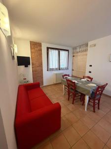 a living room with a table and a red couch at La Dimora dei Cri in Cona