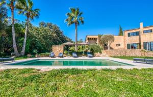a swimming pool in front of a house with palm trees at Esteva in Sant Llorenç des Cardassar