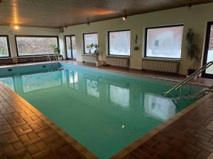 a swimming pool with green water in a building at Hotel Harzer am Kurpark in Bad Herrenalb