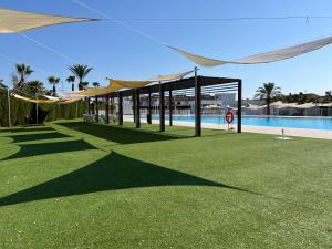 a pool with a pavilion with a grassy area and a swimming pool at Casa Moolio - Private Holiday Home with Pool Access, Walk to Beach & Restaurants in Los Alcázares +26 photos