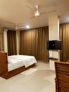 a bedroom with a bed and a flat screen tv at Casal stay in Mannārakkāt
