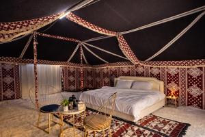 a bedroom with a bed in a tent at Desert Wonders Camp in Ḩawīyah