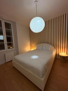 a bedroom with a large white bed and a pendant light at Charmant T2 hyper-centre, proche gare & mer in Saint-Brieuc