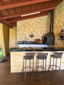 a kitchen with three bar stools and a stove at Chalé Ubajara in Ubajara