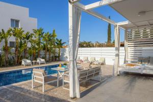 a patio with a table and chairs next to a pool at Protaras Villa Alina in Protaras