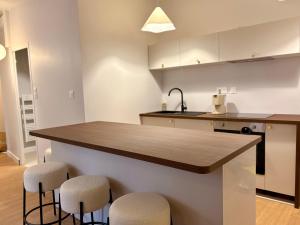 a kitchen with a counter with stools and a sink at Charmant T2 hyper-centre, proche gare & mer in Saint-Brieuc
