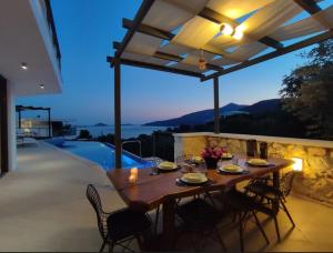 a wooden table and chairs on a patio with a pool at Villa Ship Ahoy in Kaş