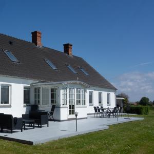 a white building with chairs and tables in front of it at Sommerliv Bed and Breakfast in Tranekær