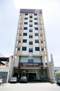 a tall white building with cars parked in front of it at Grande Hotel Ipatinga in Ipatinga