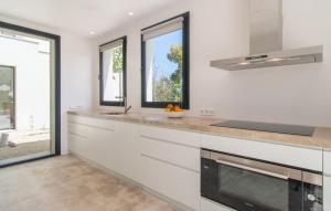 a kitchen with white cabinets and a sink and windows at Ternelles in Pollença +24 photos