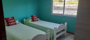 two beds in a room with blue walls and a window at cabañas sunrise in Merlo