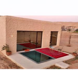 a house in the desert with a red carpet at Desert Wonders Camp in Ḩawīyah