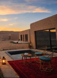 a patio with two chairs and a table on a rug at Desert Wonders Camp in Ḩawīyah