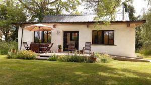 a small white house with chairs and an umbrella at 2 Bed in Haughley oc-strb in Haughley