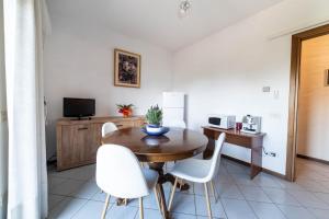 a dining room with a wooden table and white chairs at Casa Wanda LAWANDA in Oristano