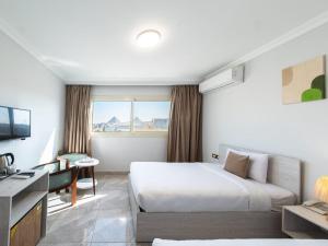a hotel room with a bed and a desk and a television at Sunshine Pyramids& Grand Museum View in Cairo