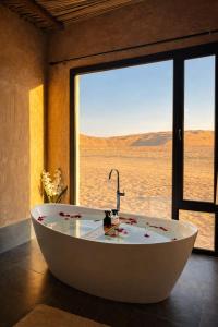 a bath tub in a room with a large window at Desert Wonders Camp in Ḩawīyah +42 photos