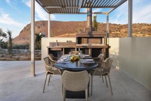a table and chairs on a patio with a grill at Utopia Luxury Villas in Gouves