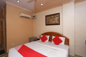 a bedroom with a bed with red and white pillows at Hotel O Madhur Regency in Meerut