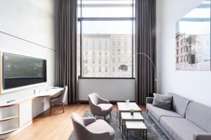ein Wohnzimmer mit Sofa, Sesseln und Fernseher in der Unterkunft Hotel MOA Berlin in Berlin
