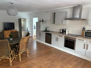a kitchen with white cabinets and a table with chairs at Gästezimmer Flechtorf in Lehre