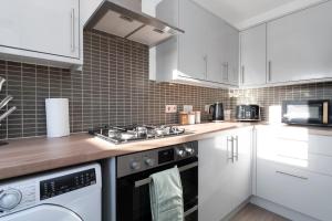 a kitchen with white cabinets and a stove top oven at Buie's Runway Retreat in EDI
