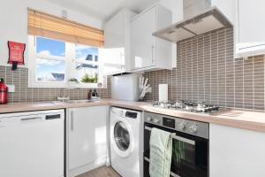 a kitchen with white cabinets and a washer and dryer at Buie's Runway Retreat in EDI +21 photos
