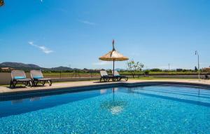 a swimming pool with two chairs and an umbrella at Catalina in Alcudia