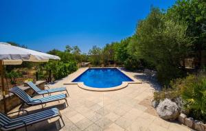 a swimming pool with two chairs and an umbrella at Sos Monjos in Artá