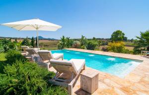 a swimming pool with chairs and an umbrella at Son Artigues in Manacor