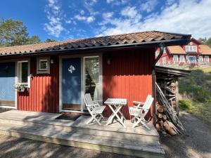 a red house with chairs and a table on a deck at Cozy Studio on Utö Near Beach & Restaurant in Utö