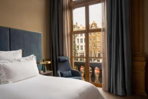 a bedroom with a bed and a chair and a window at Rosewood Amsterdam in Amsterdam +50 photos