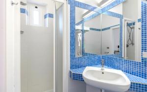 a blue tiled bathroom with a sink and a shower at Hotel Brig in Cattolica