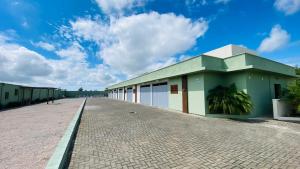 a building on a brick road with a cloudy sky at Pousada Jabuticabeira in Jaguaruna