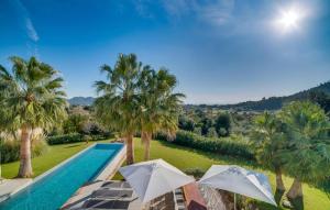 a pool with two umbrellas and palm trees at Son Sard Nou in Son Servera