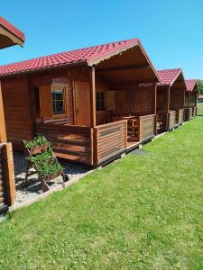 a large wooden cabin with a grass yard at Domki letniskowe Wrzoski in Kamień Pomorski