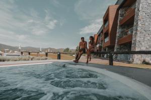 two men are standing next to a swimming pool at Böden Hotel & Spa, AKEN SOUL in Villa General Belgrano