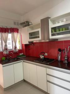 a kitchen with white cabinets and red walls at Miramar2026 in Miramar +4 photos