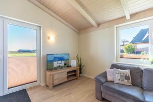 a living room with a couch and a flat screen tv at Ferienhaus Strandflieder in Dagebüll