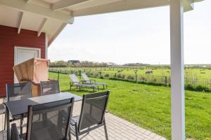 a patio with chairs and tables and a field at Ferienhaus Strandflieder in Dagebüll