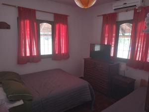a bedroom with red curtains and a bed and a television at CABAÑAS LA PILARICA in San Rafael